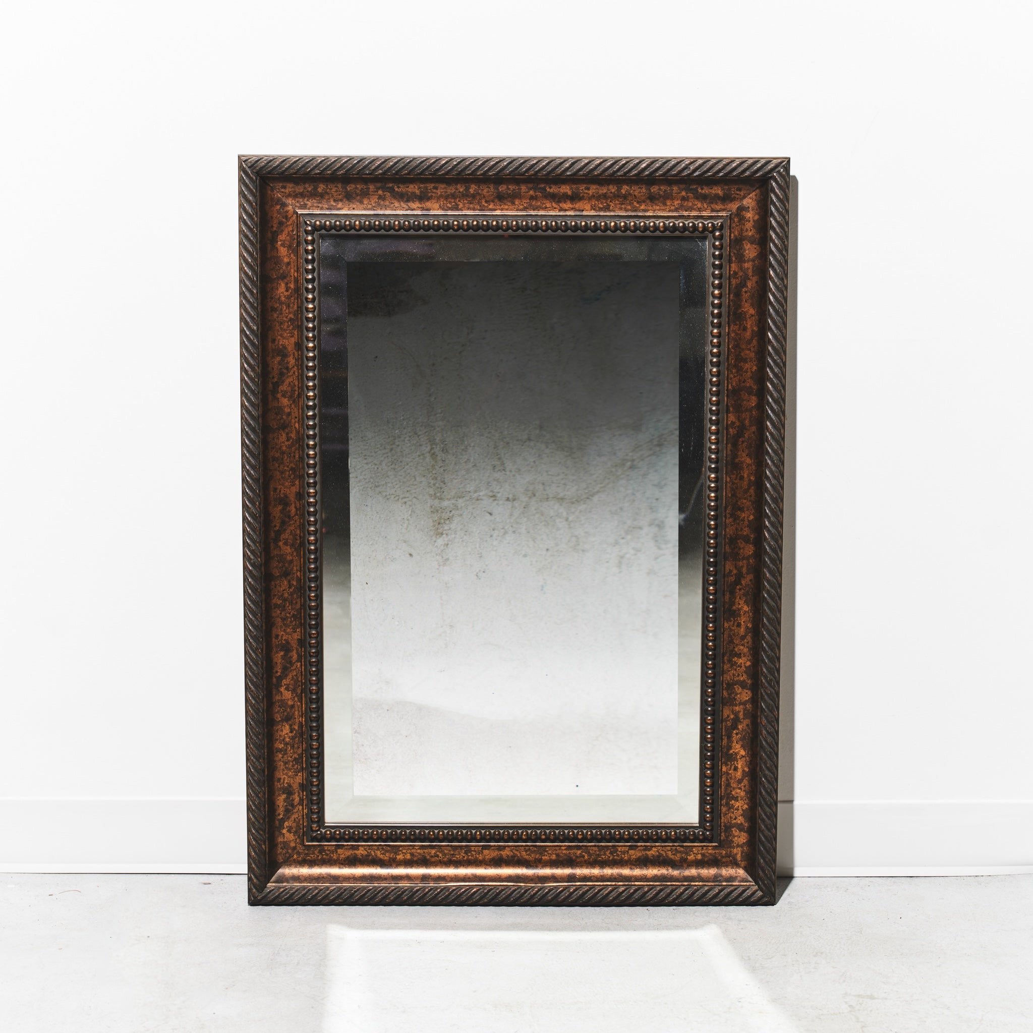 Rectangular mirror with decorative brown frame on a white background