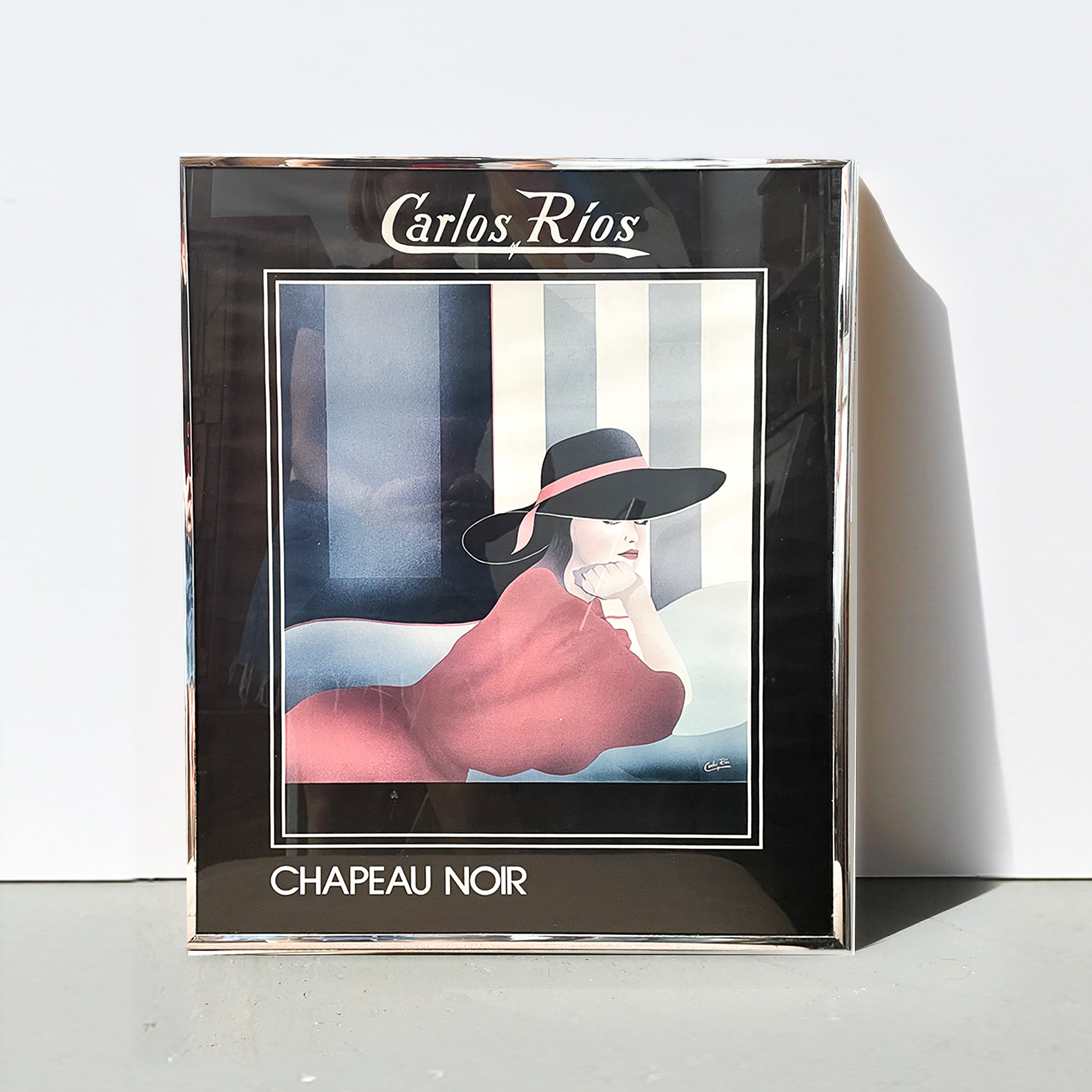 Framed artwork by Carlos Rios featuring a woman in a black hat with the title 'Chapeau Noir'.
