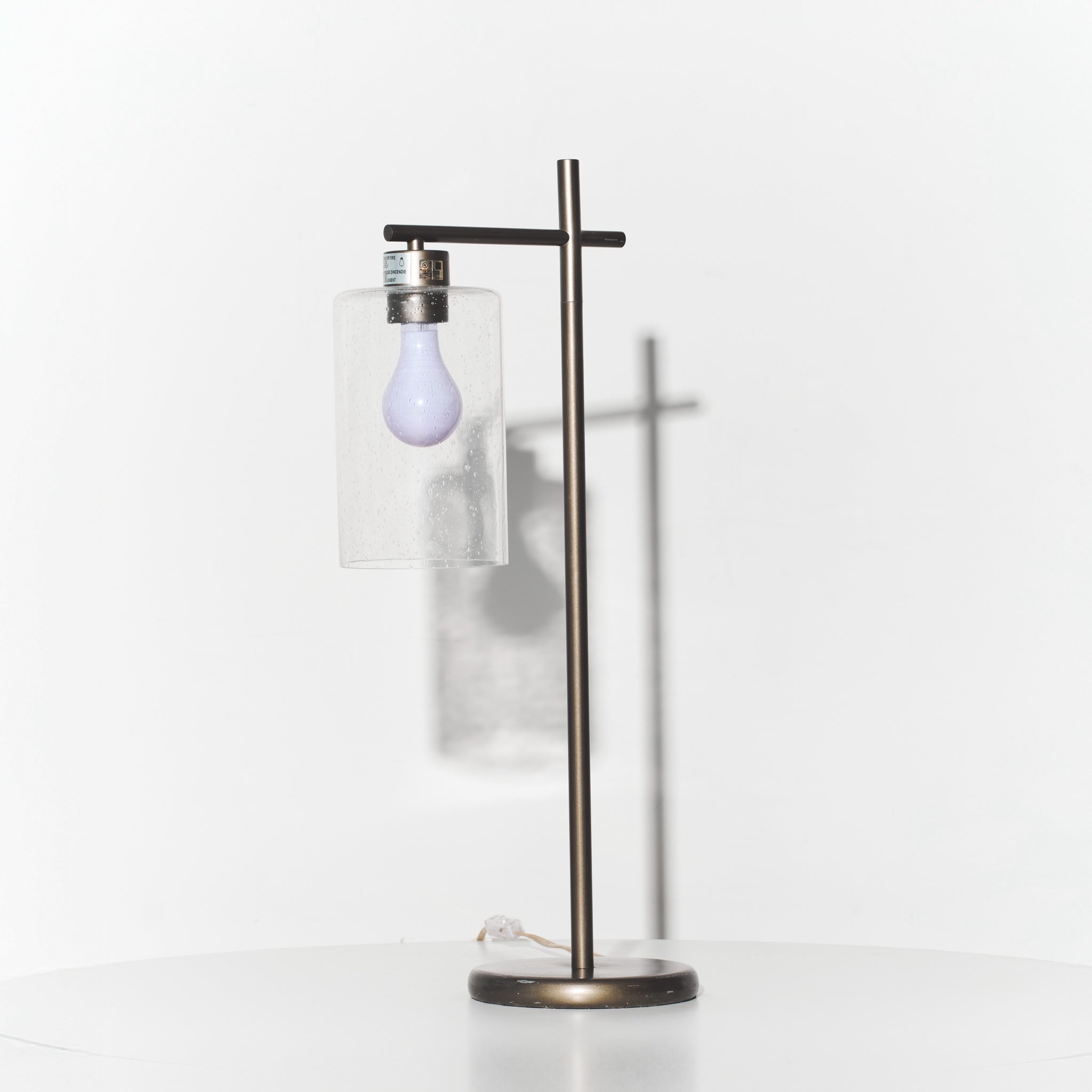 Modern floor lamp with a glass shade and exposed light bulb on a white background