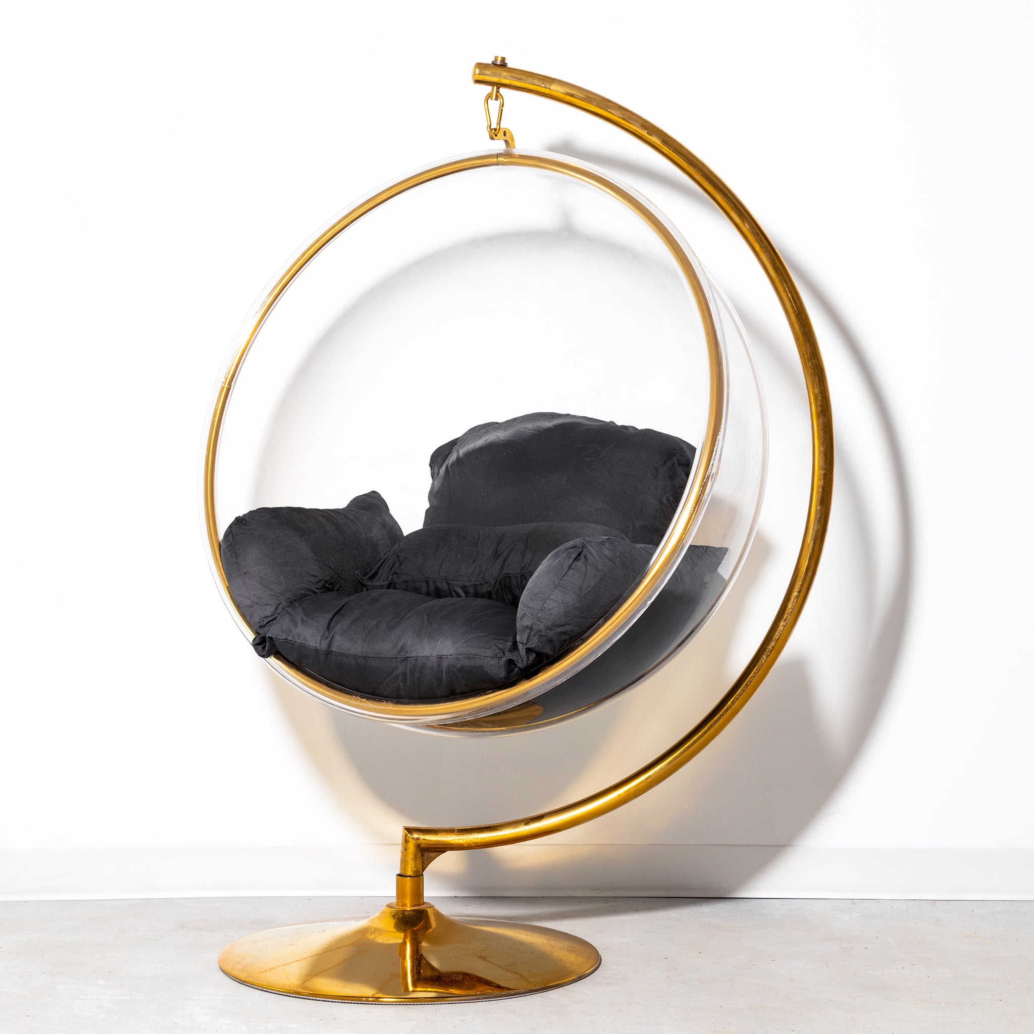 Hanging bubble chair with gold stainless steel base, clear acrylic shell, and black cushions with pre-washed removable covers