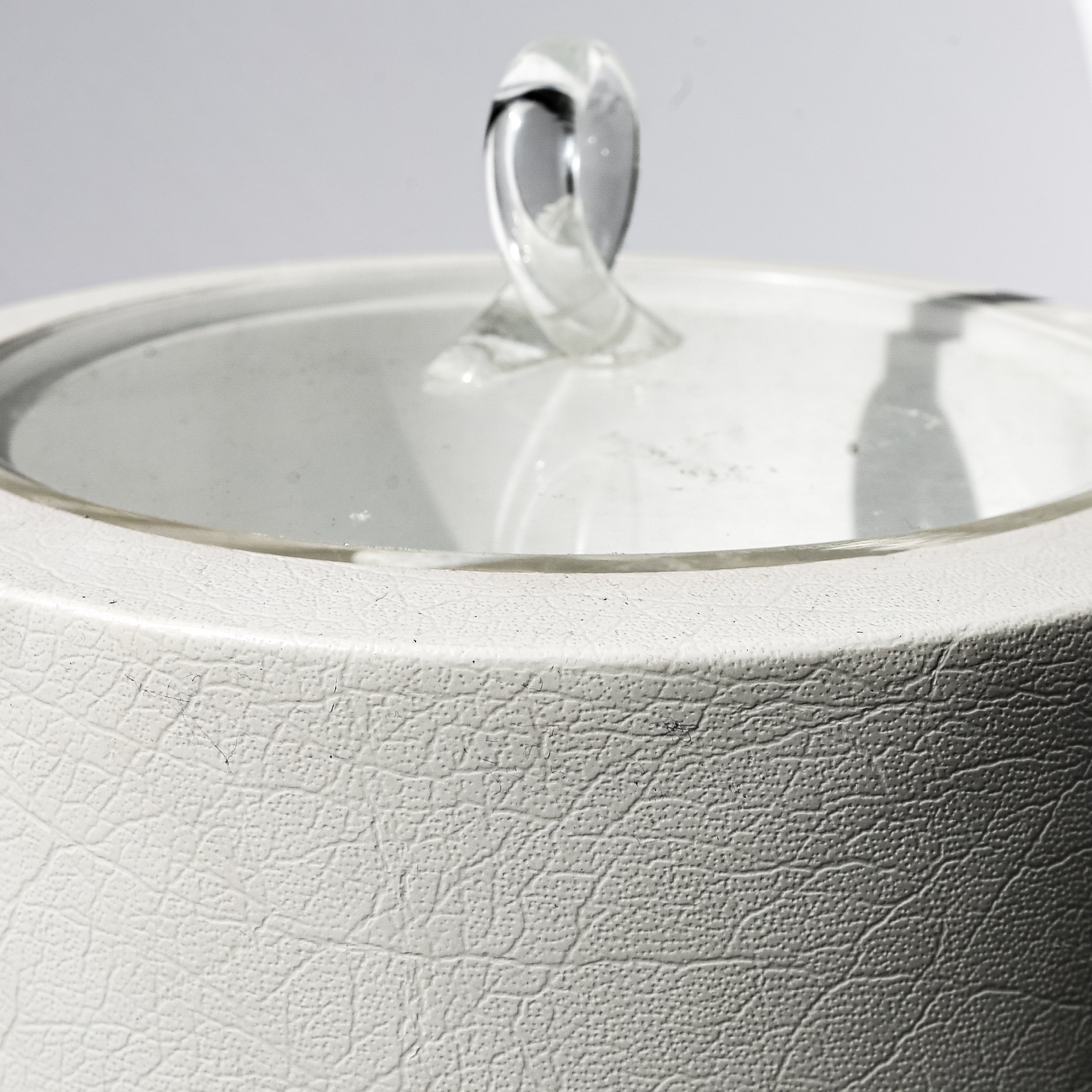Close-up of a white ceramic teapot with a silver lid and handle on a light gray background.