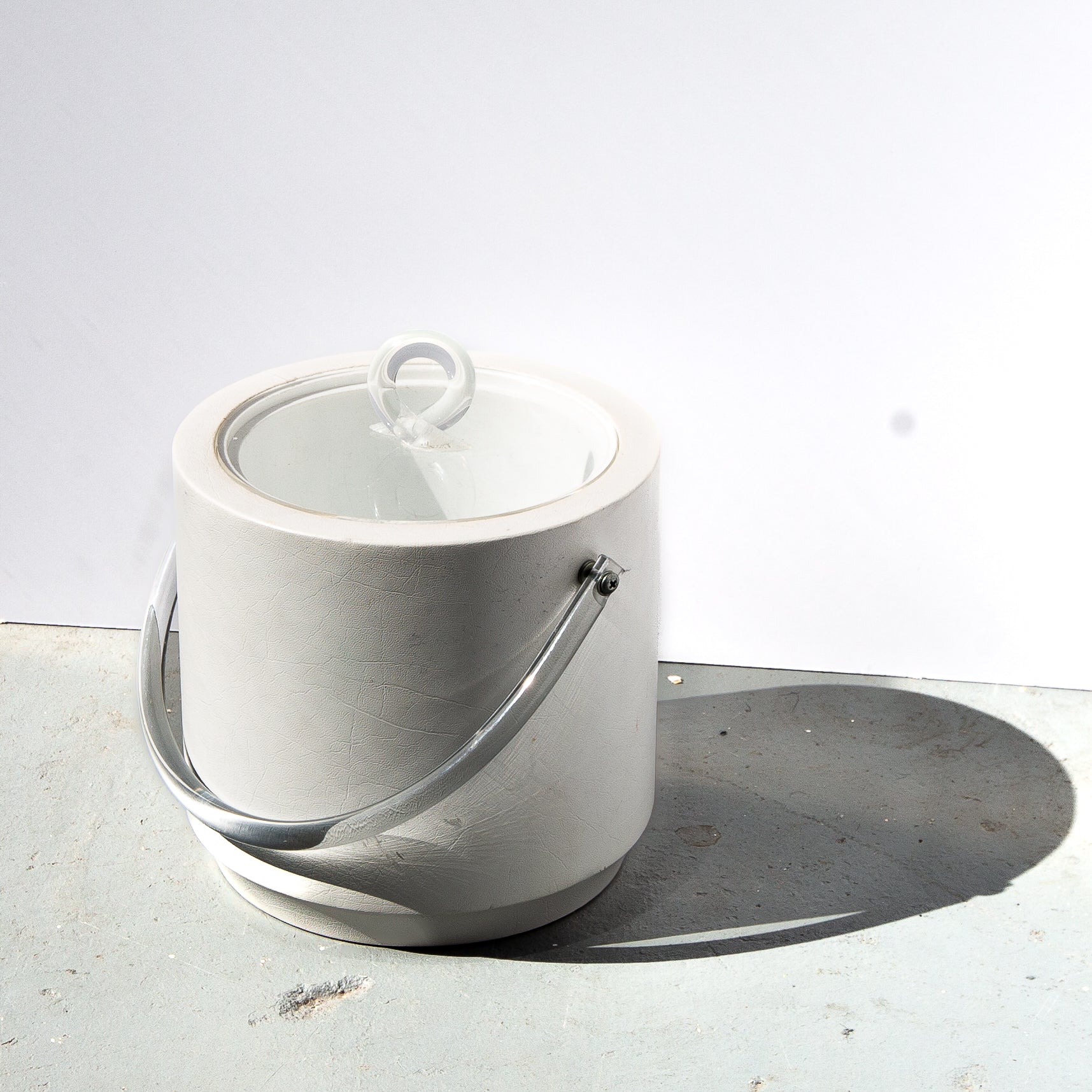 White marble ice bucket with a lid on a light gray surface