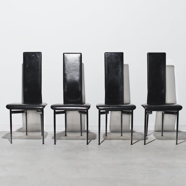 Four black chairs with high backs on a white background