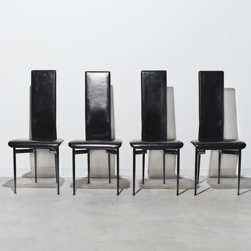 Four black chairs with high backs on a white background