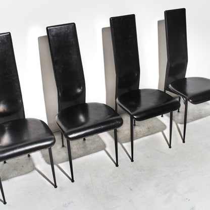 Set of five black chairs with high backs on a concrete floor.