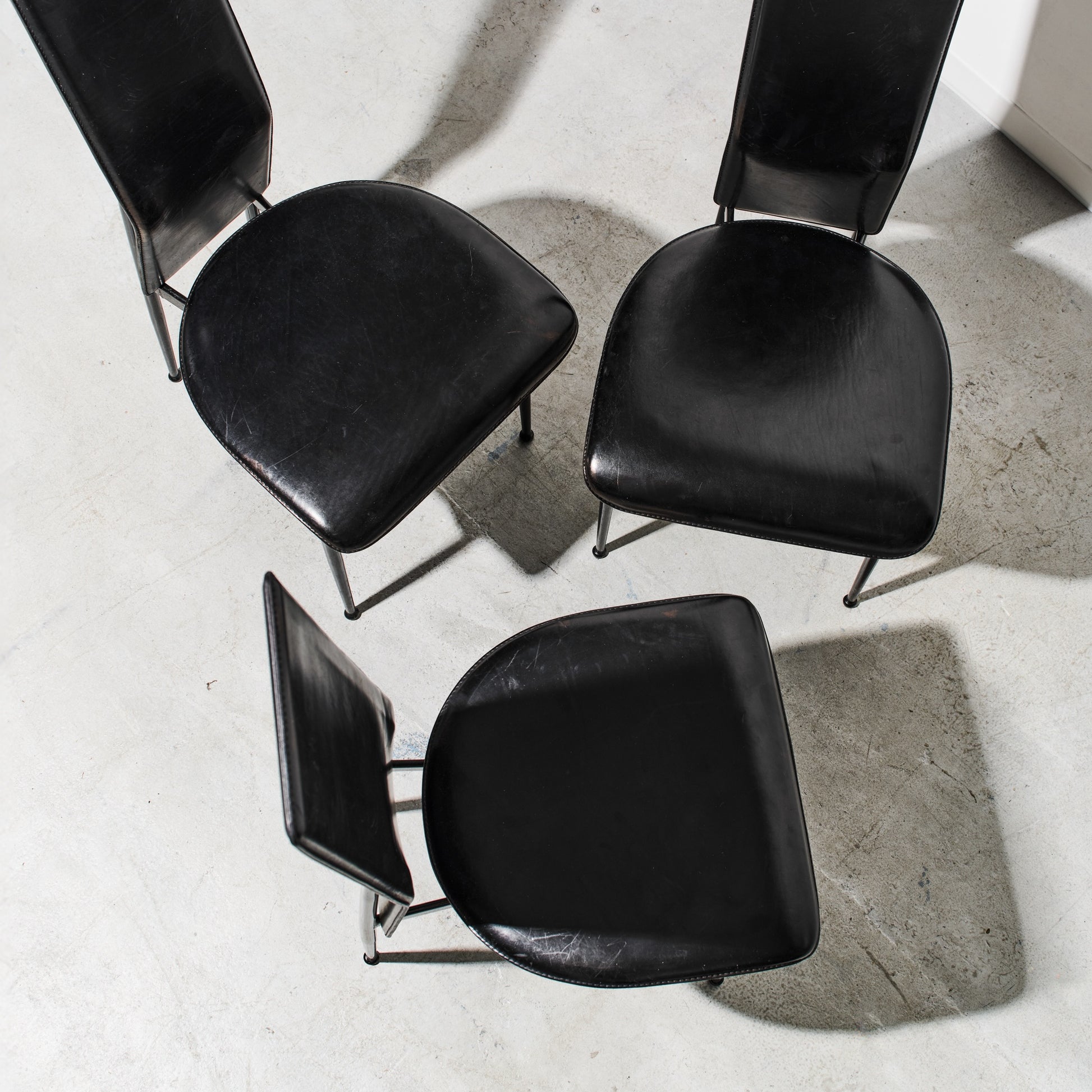Four black chairs arranged in a circle on a concrete floor.