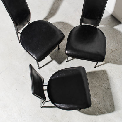 Four black chairs arranged in a circle on a concrete floor.