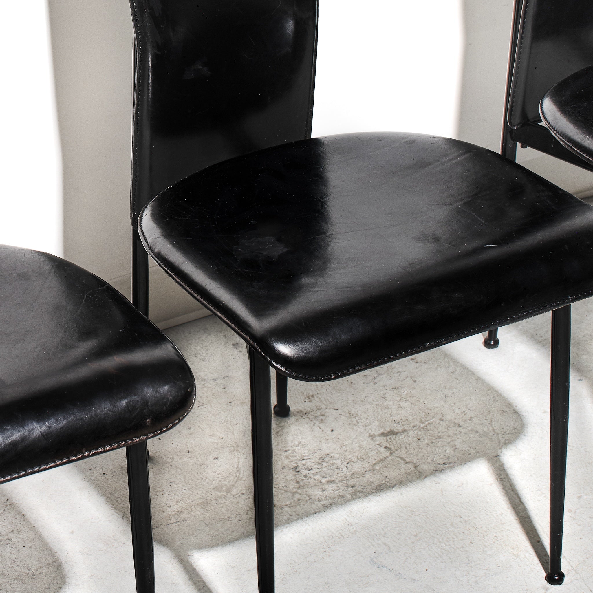 Black leather chairs with metal legs on a light-colored floor.