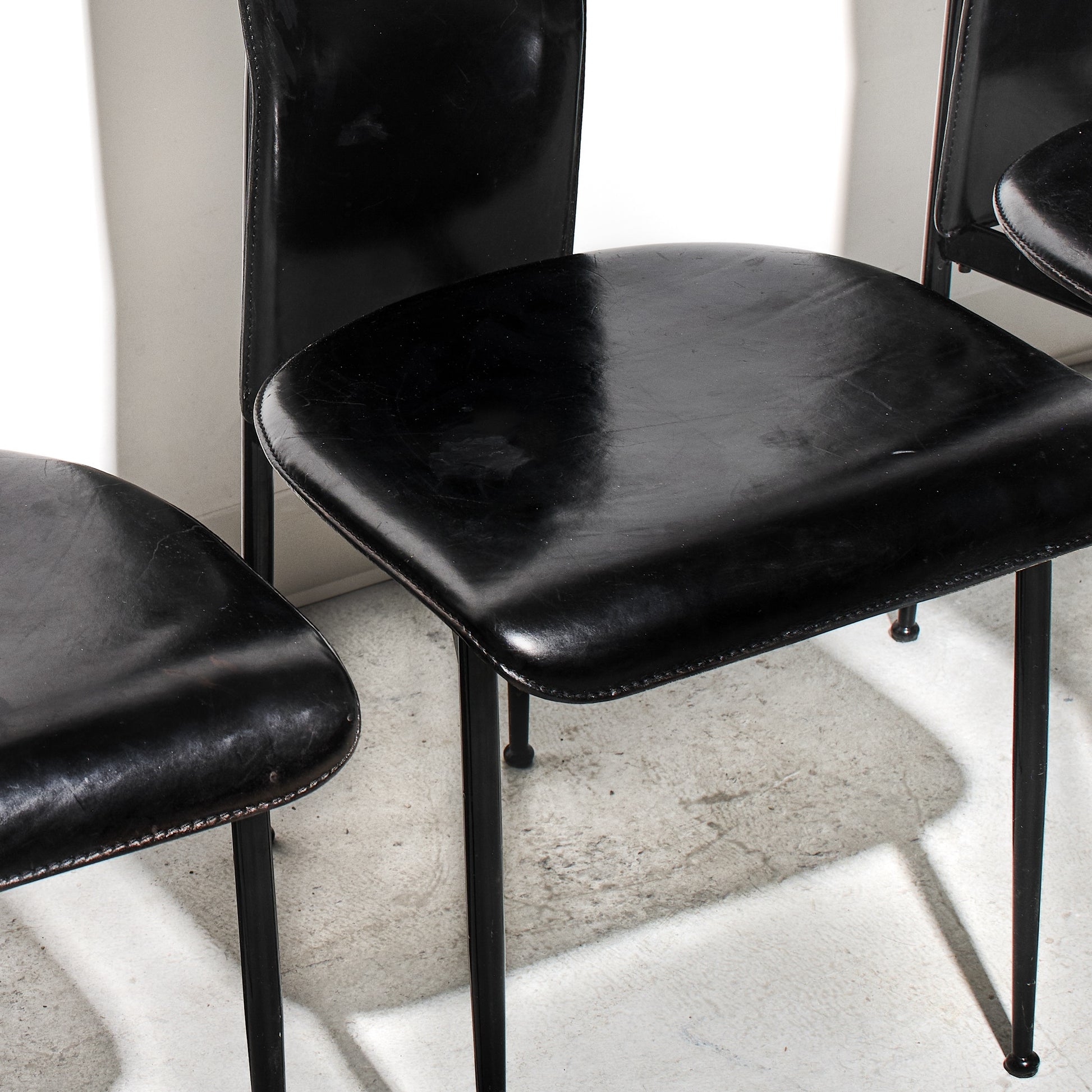 Black leather chairs with metal legs on a light-colored floor.