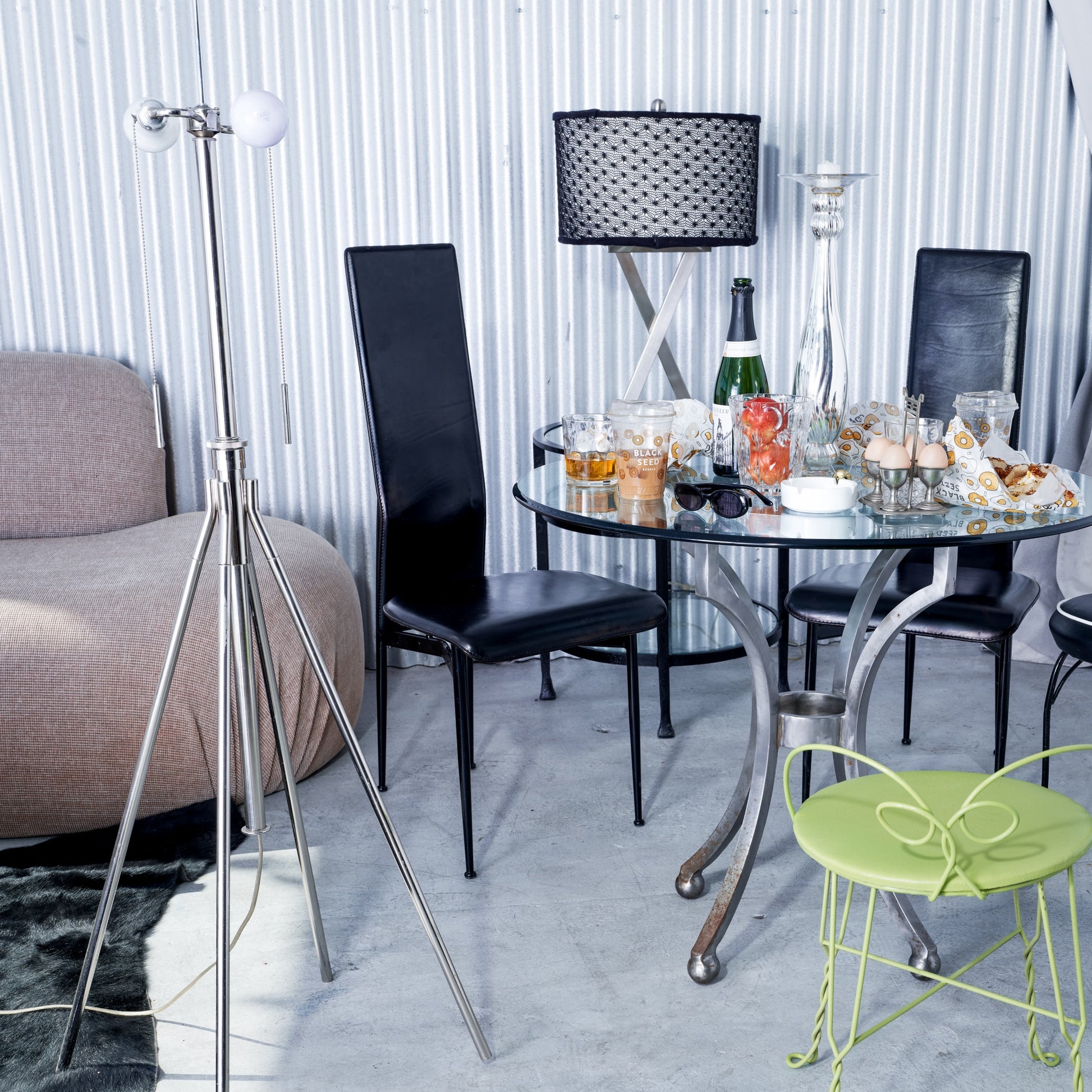 Modern living room with a round glass table, black chairs, and a green chair.