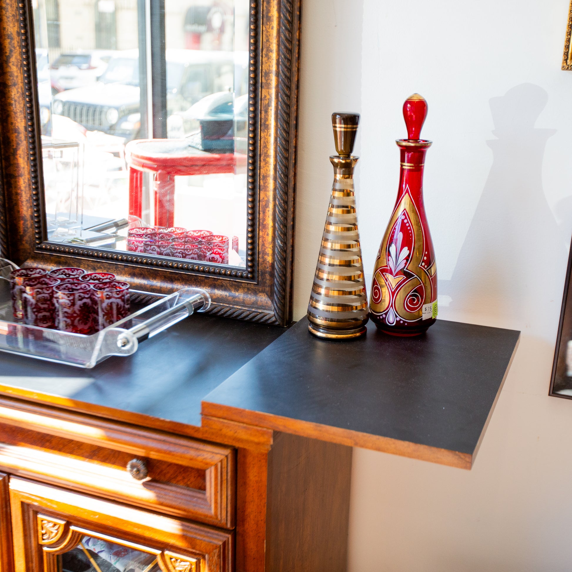 Decorative items on a wooden surface with a mirror reflecting an outdoor scene.