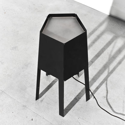 Black hexagonal lamp on a light gray concrete floor