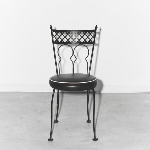 Black metal chair with decorative backrest on a light gray floor and white background