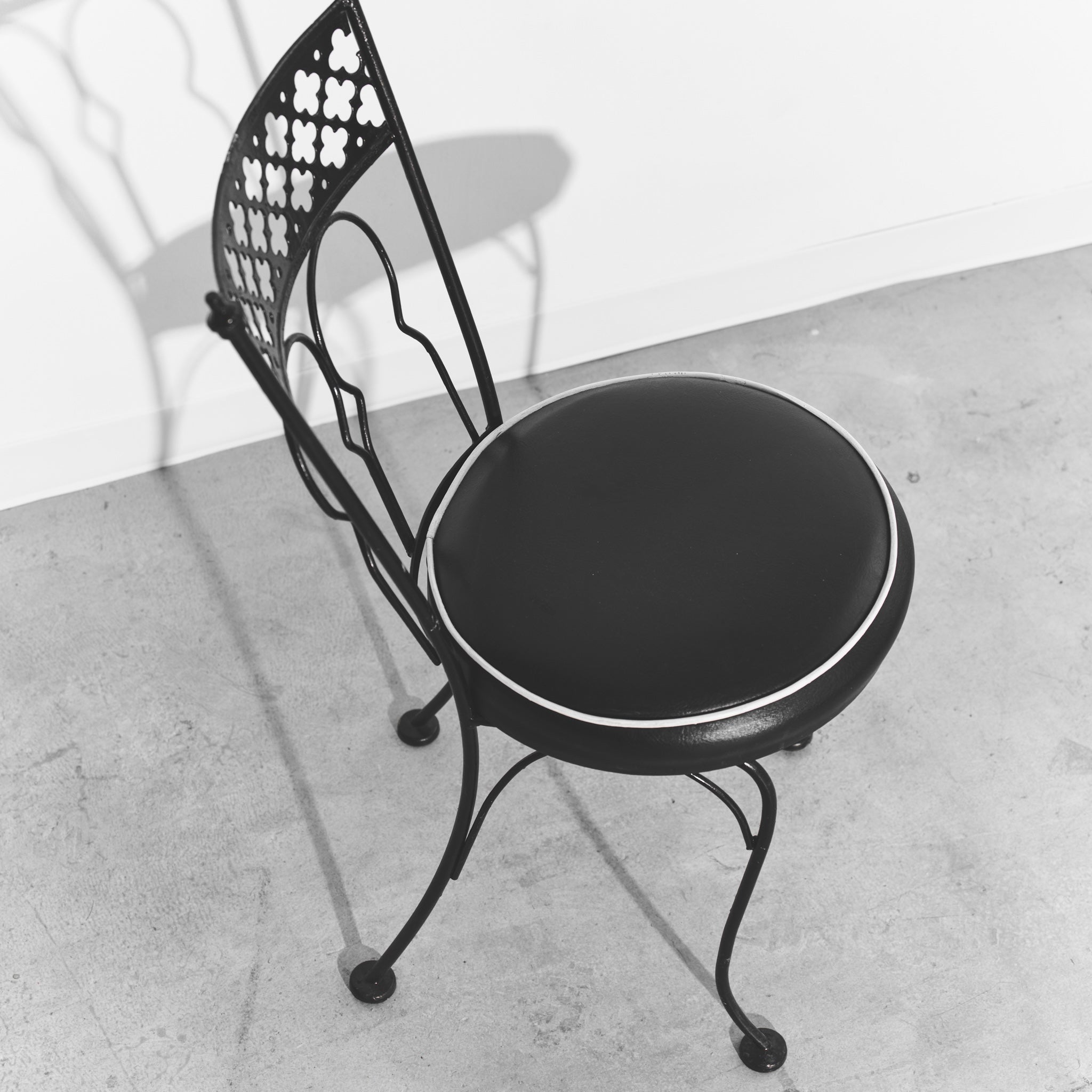 Black metal chair with round cushioned seat on a concrete floor