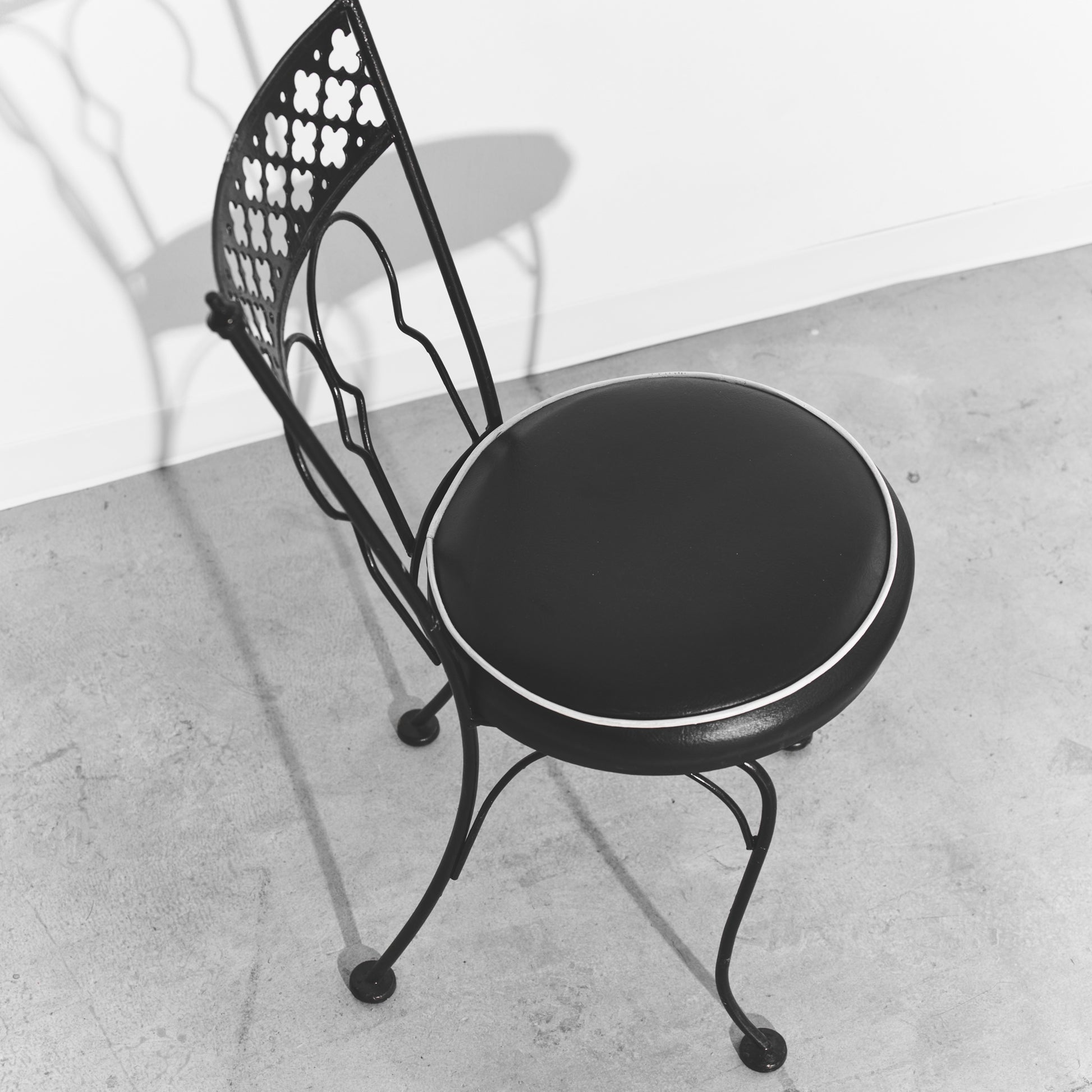 Black metal chair with round cushioned seat on a concrete floor
