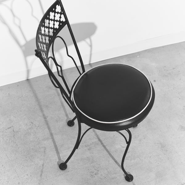 Black metal chair with round cushioned seat on a concrete floor