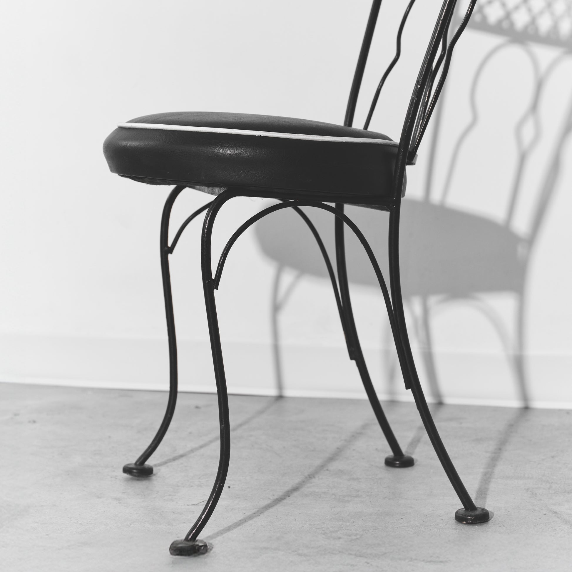 Black metal chair with cushioned seat on a light wooden floor.