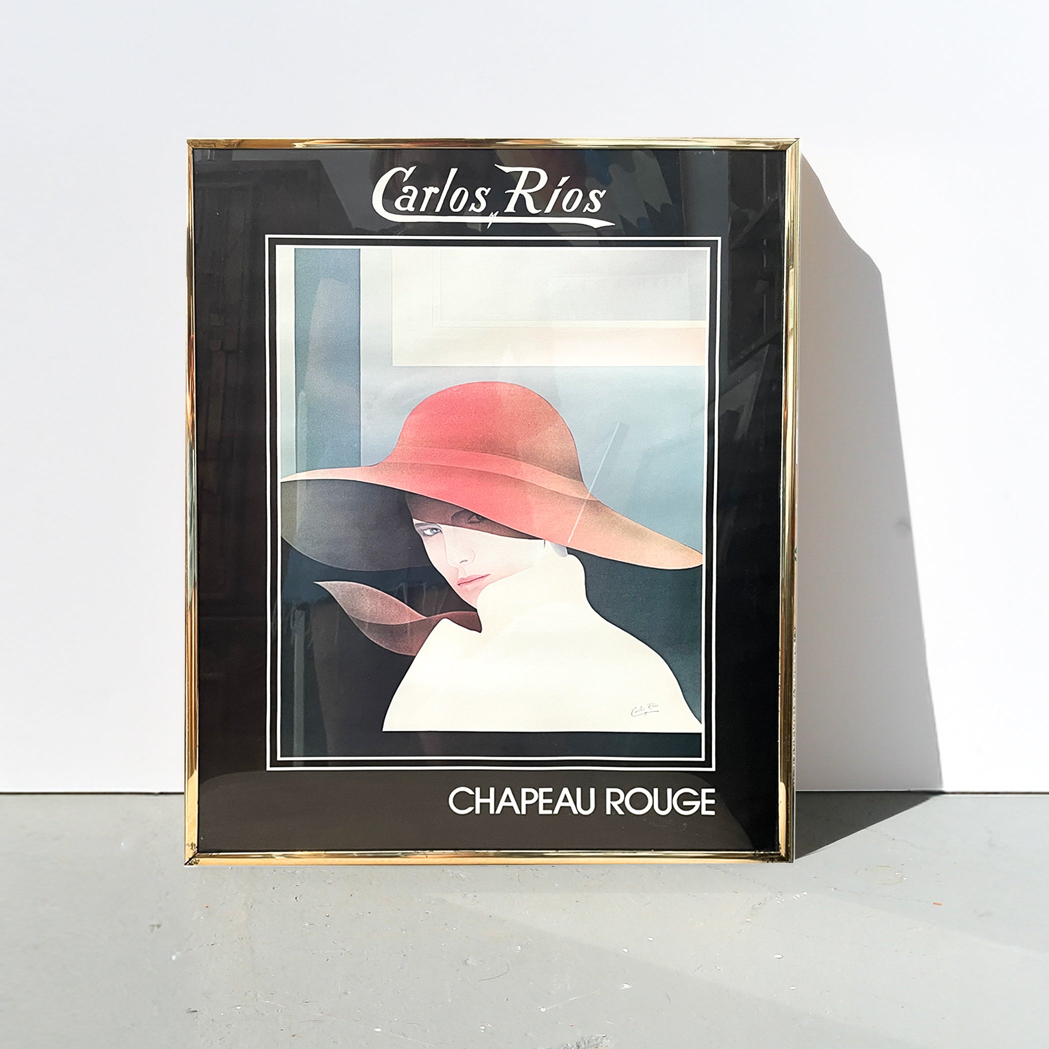 Framed artwork titled 'Chapeau Rouge' by Carlos Rios on a white background