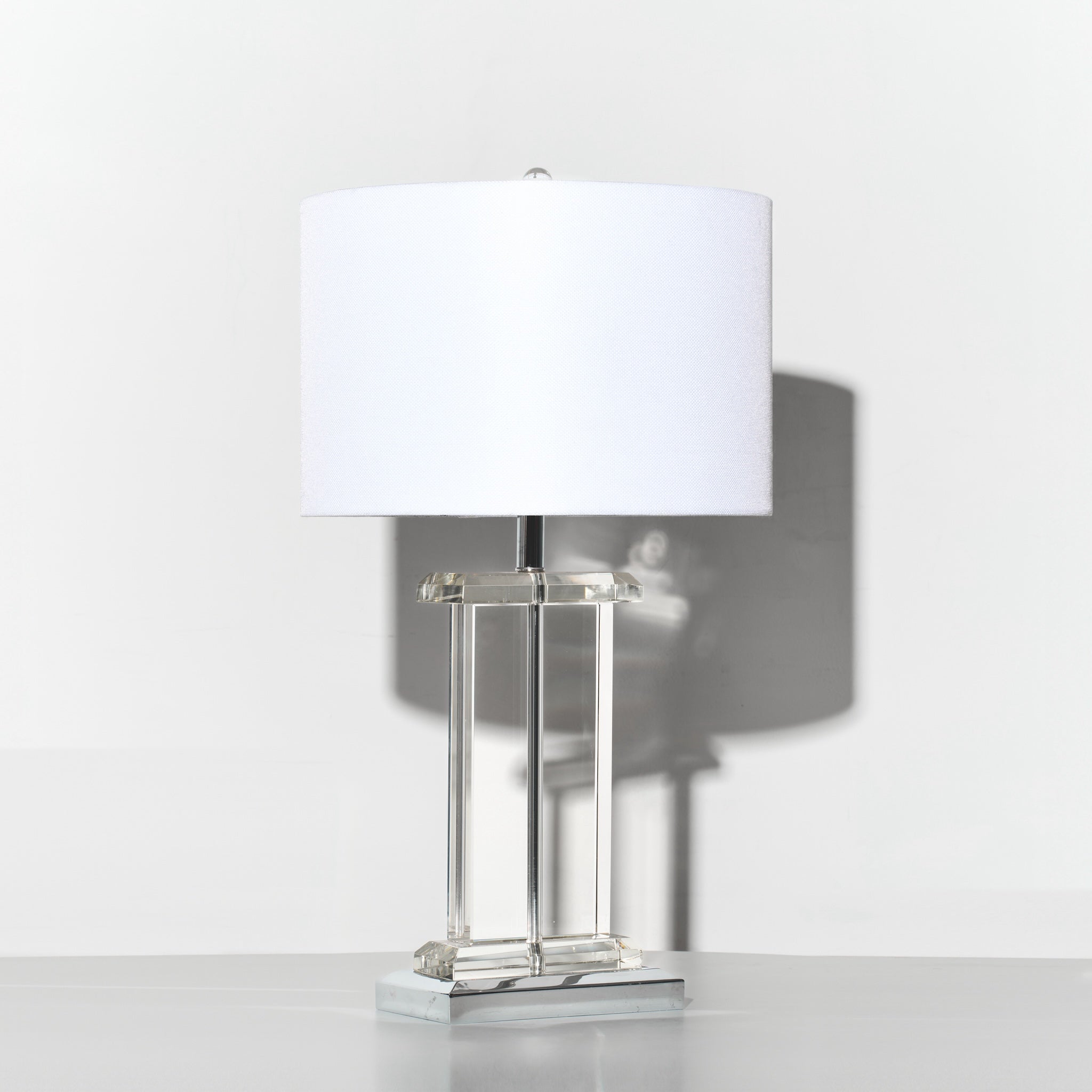 Table lamp with a white shade on a reflective surface with a light gray background
