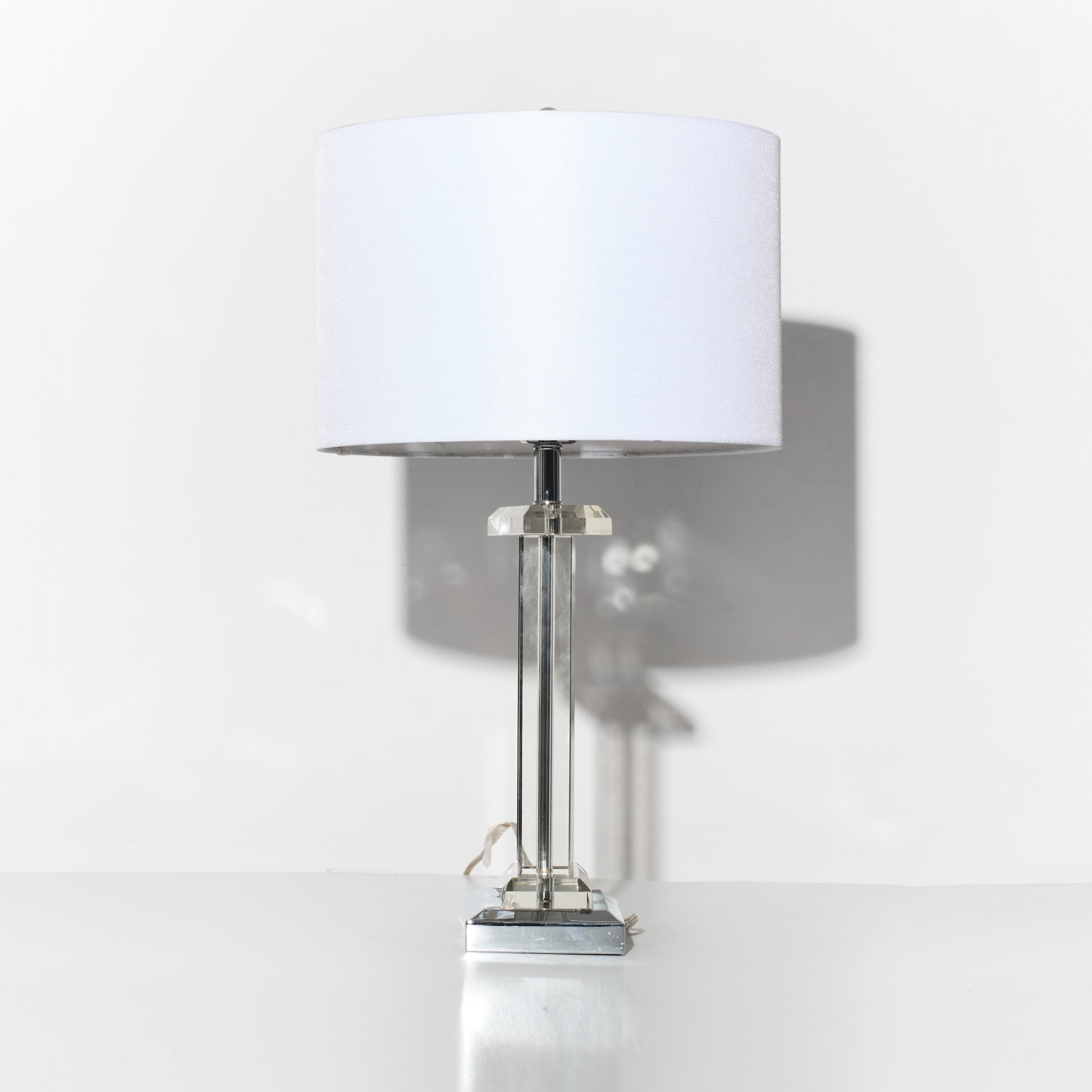 Table lamp with a white shade on a reflective surface