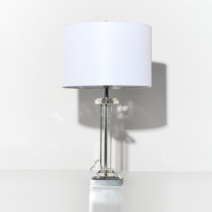 Table lamp with a white shade on a reflective surface