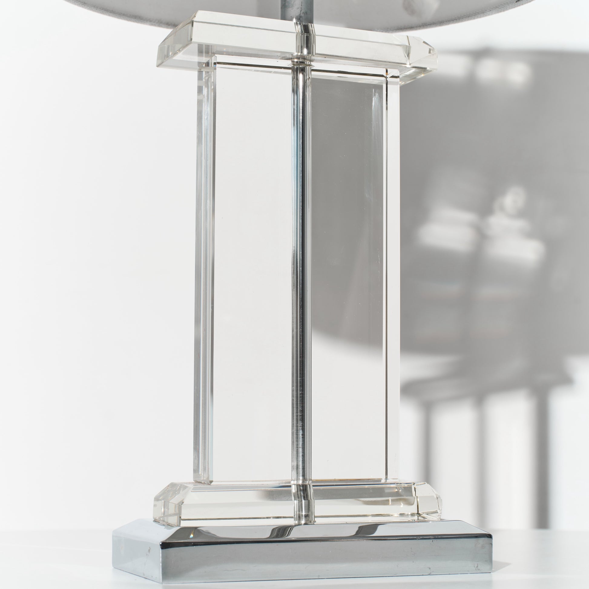 Clear glass table lamp with metallic base on a white background