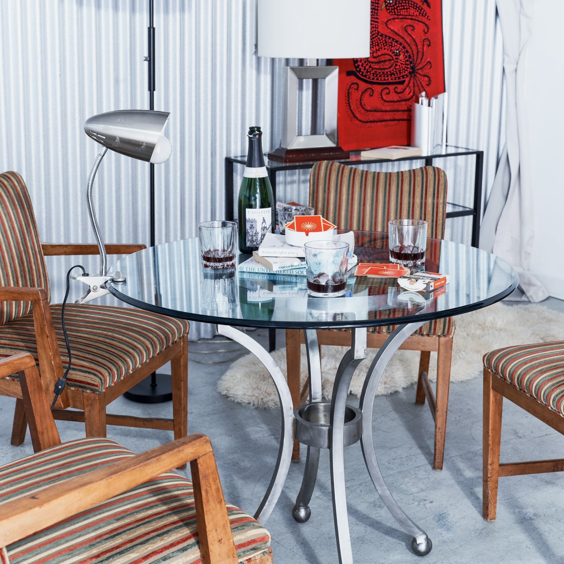 Dining room with a glass table and striped chairs, featuring a bottle and glasses.