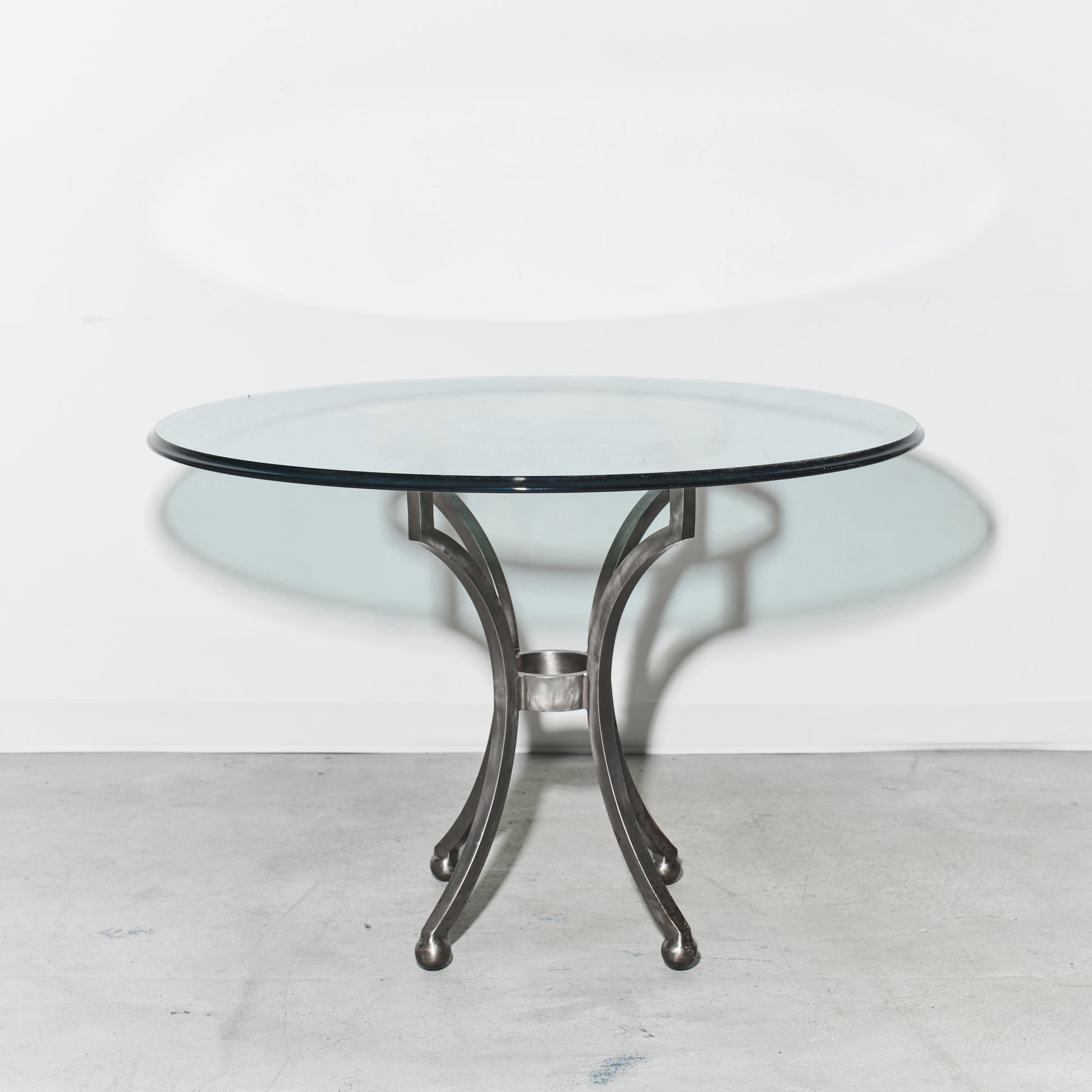 Round glass table with metal base on a white background