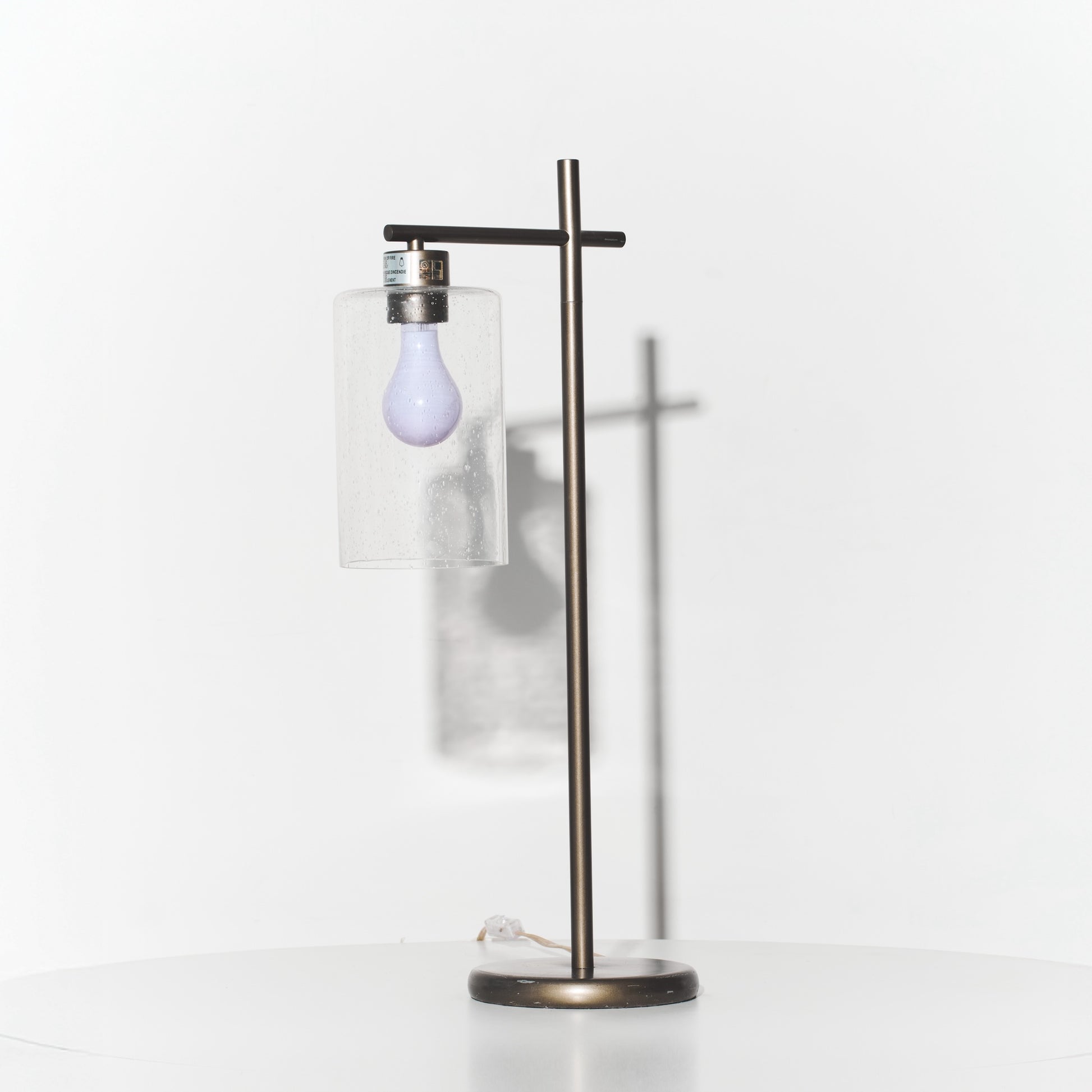 Modern floor lamp with a glass shade and exposed light bulb on a white background