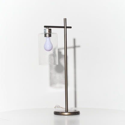 Modern floor lamp with a glass shade and exposed light bulb on a white background