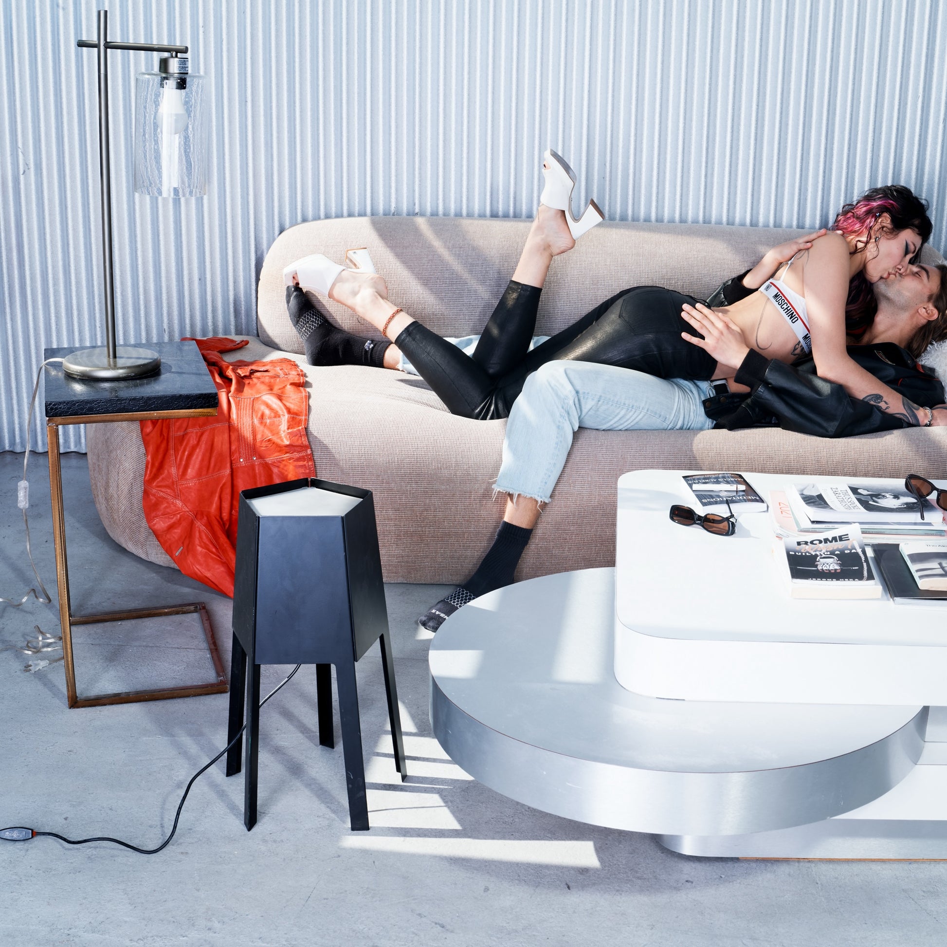 Two people lying on a beige sofa in a modern living room with a coffee table and decorative items.