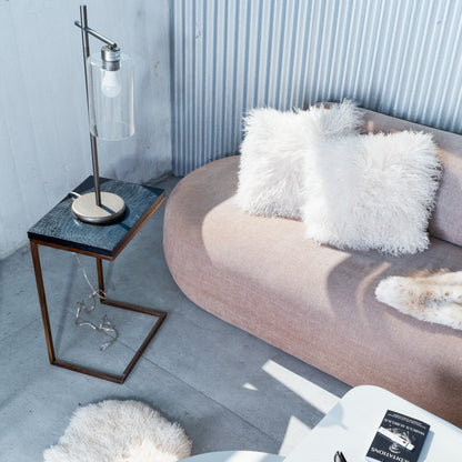 Modern living room with a pink sofa, white fluffy pillows, and a side table with a lamp.