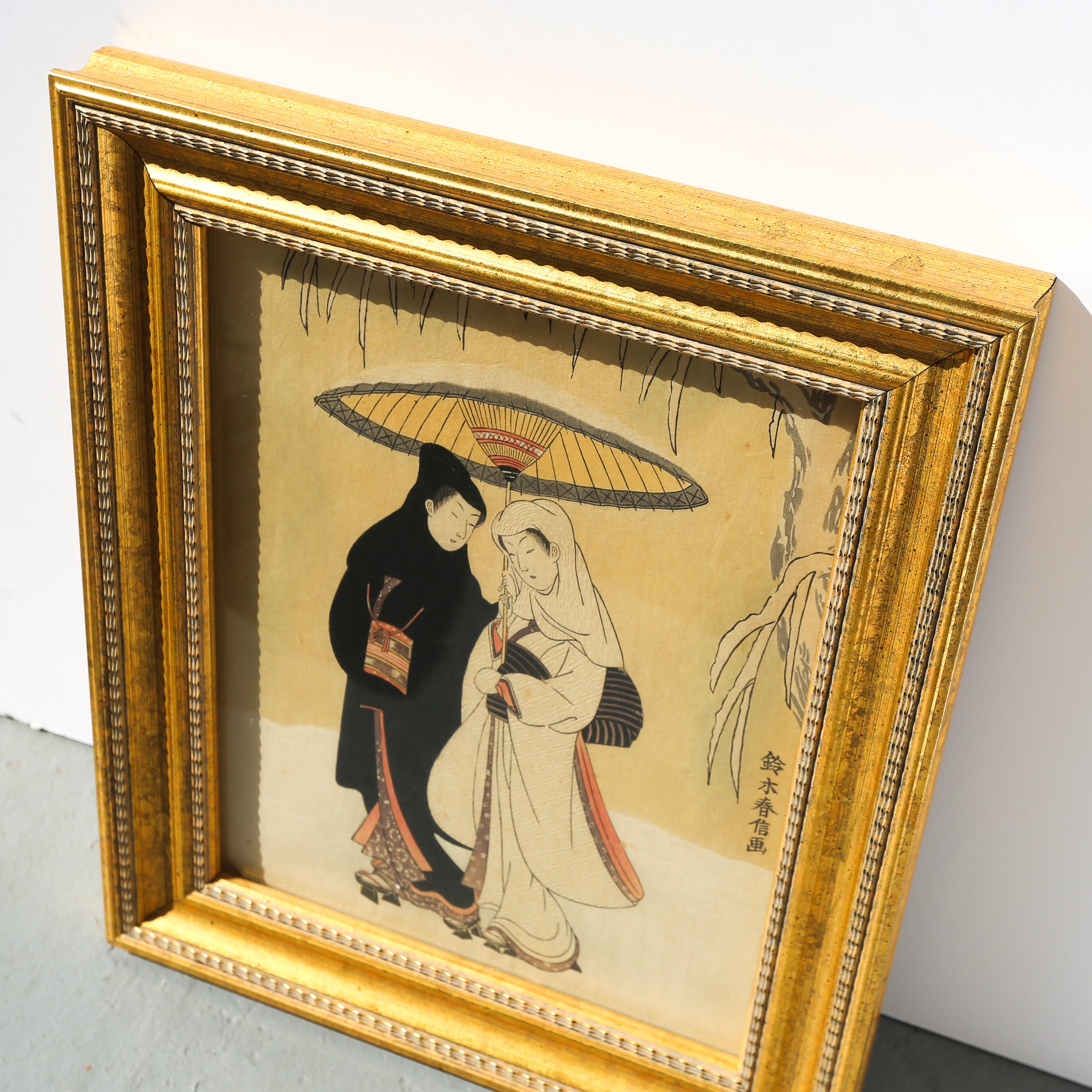 Framed artwork of two people under an umbrella on a beige background