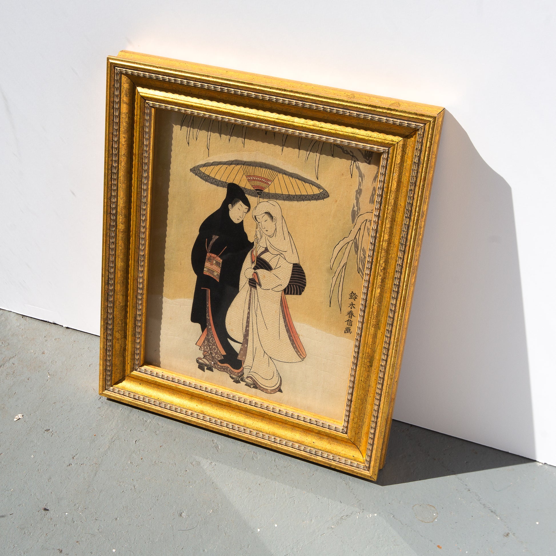 Framed artwork of two people under an umbrella on a white background