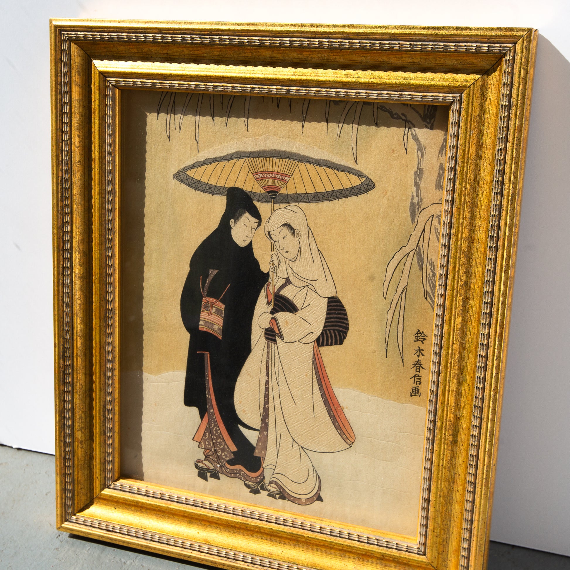 Framed artwork of two people under an umbrella on a beige background