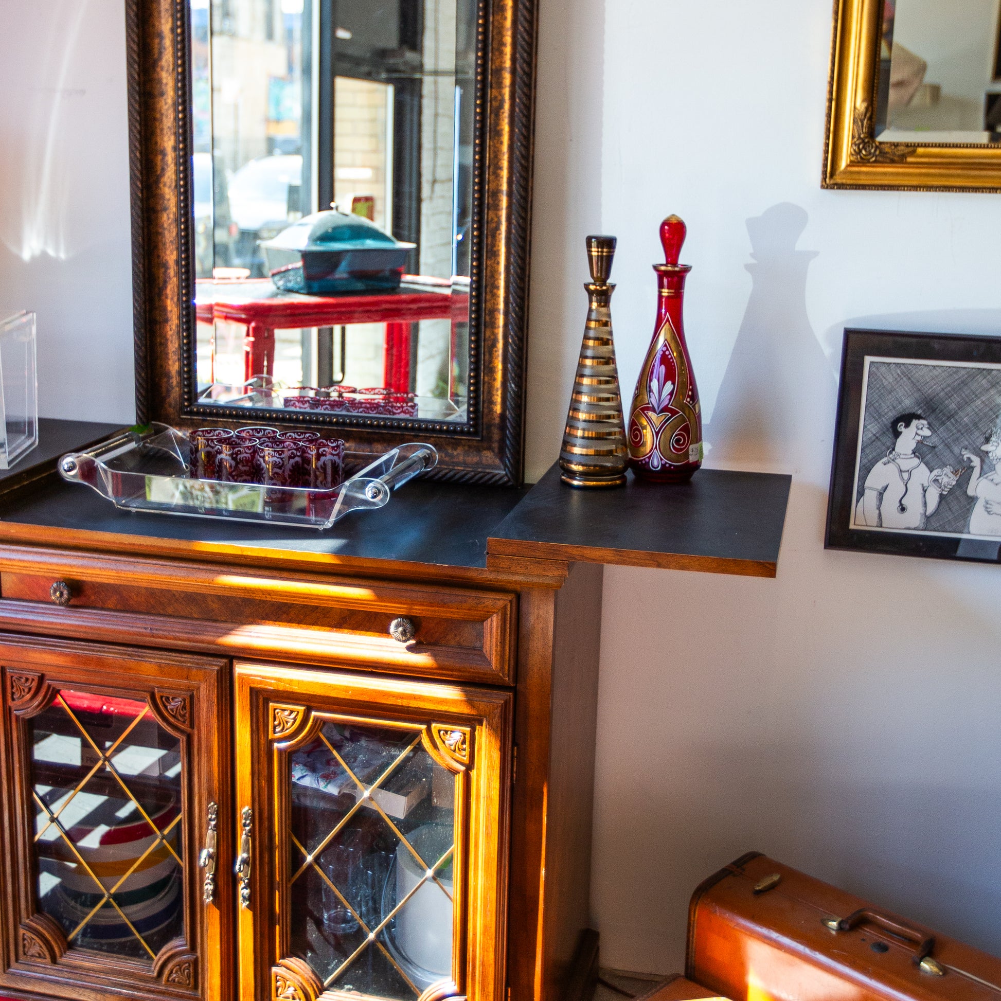 Wooden cabinet with glass doors and decorative items on a shelf.