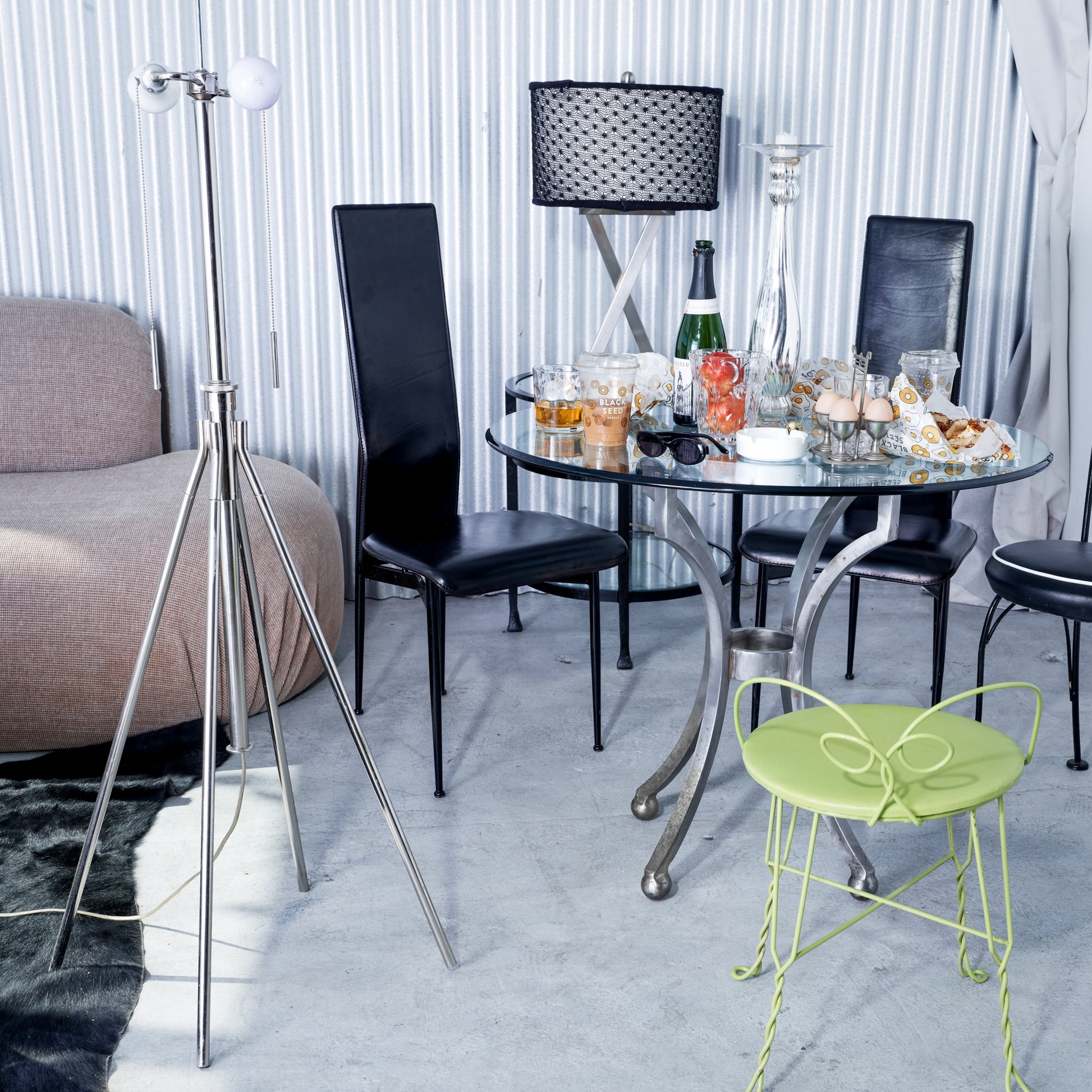 Dining area with a round glass table, black chairs, and a green chair.