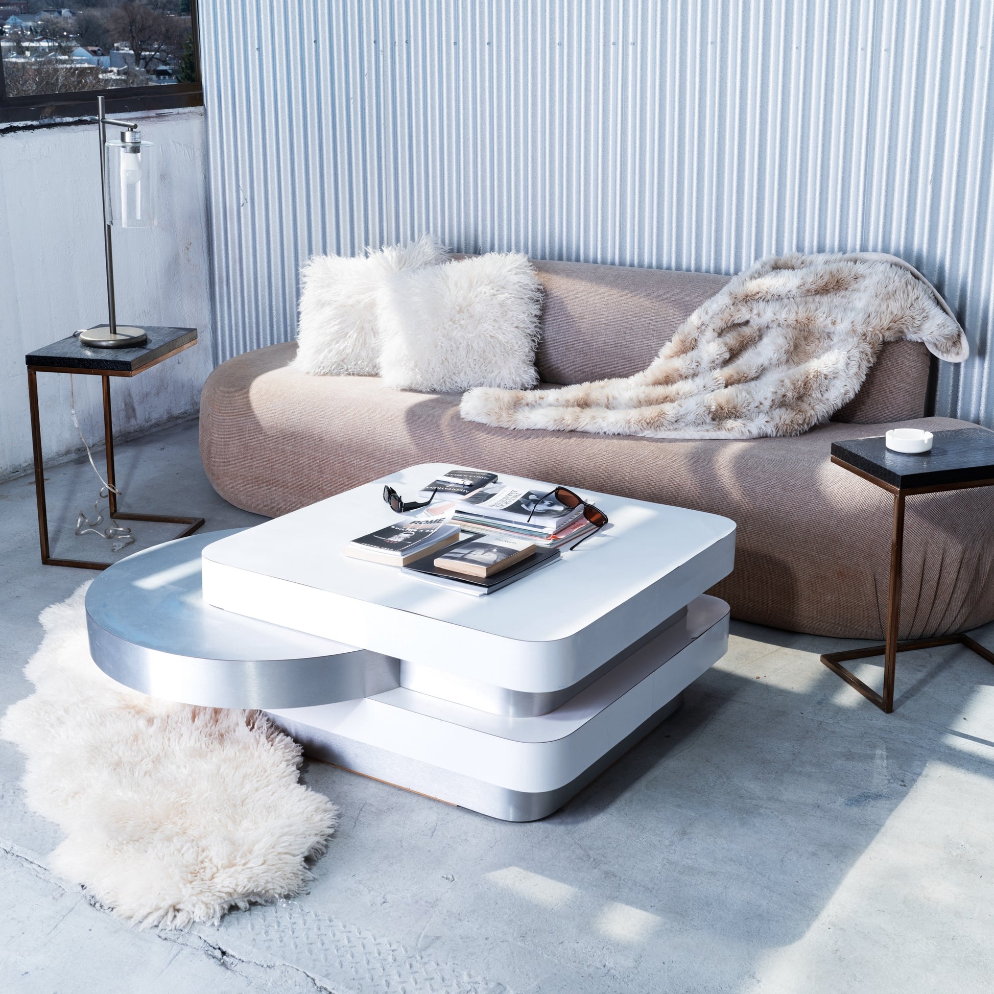 Modern living room with a beige sofa, white coffee table, and decorative items.