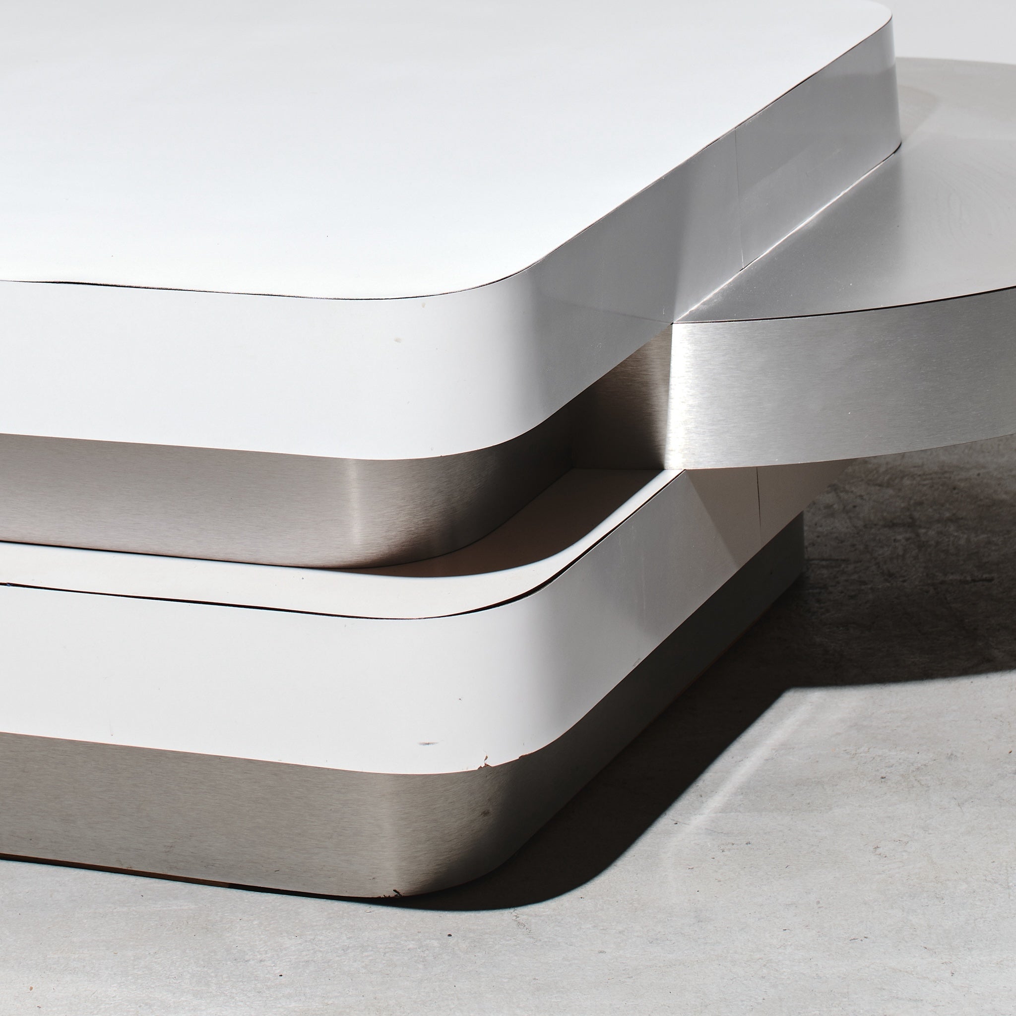 Modern metallic sculpture with wavy design on a neutral background