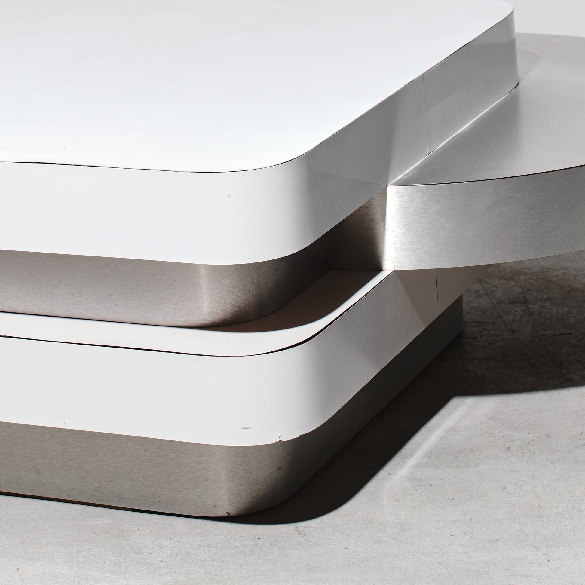 Modern metallic sculpture with wavy design on a neutral background