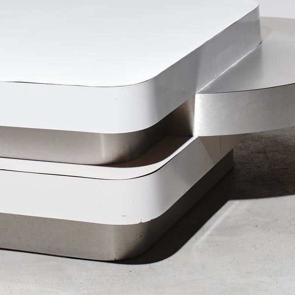 Modern metallic sculpture with wavy design on a neutral background