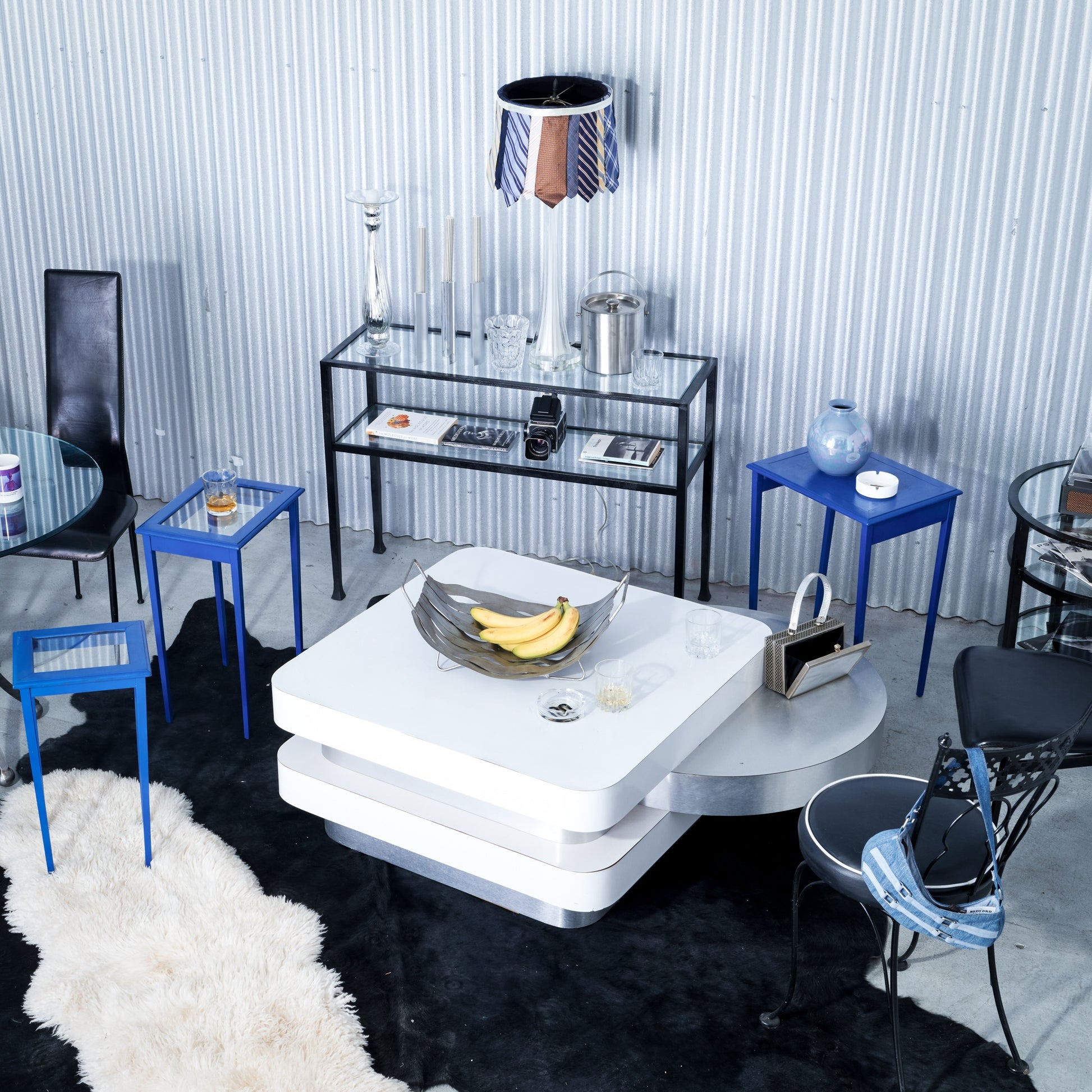 Modern living room with a white coffee table, blue chairs, and decorative items.