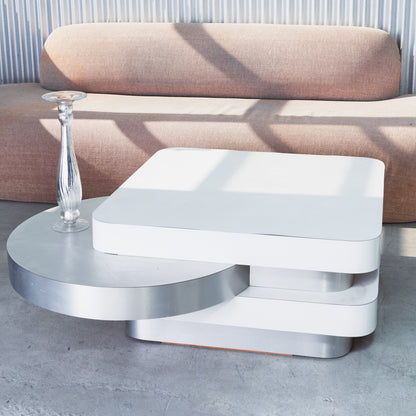 Modern white coffee table with a glass vase on a concrete floor.