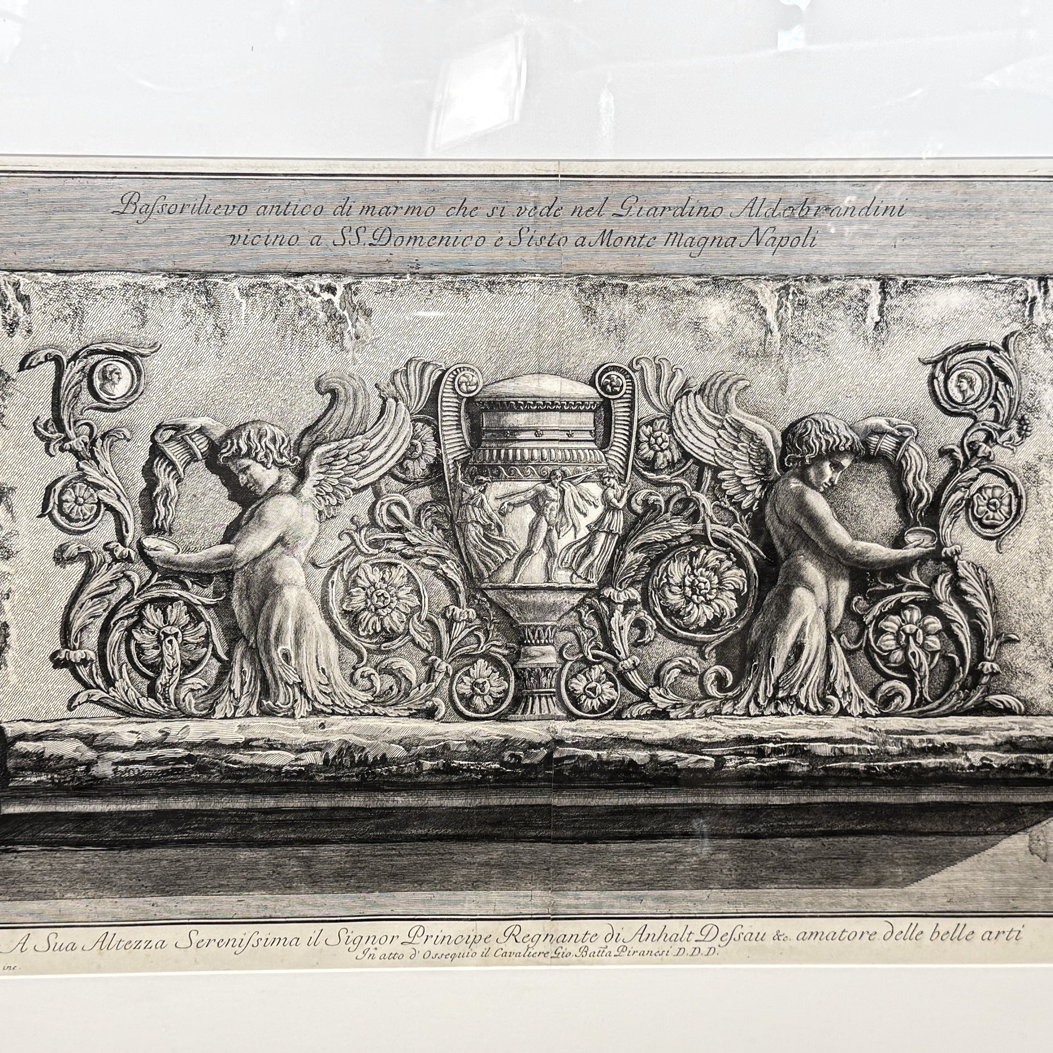 Decorative stone relief with cherubs and an urn on a marble surface