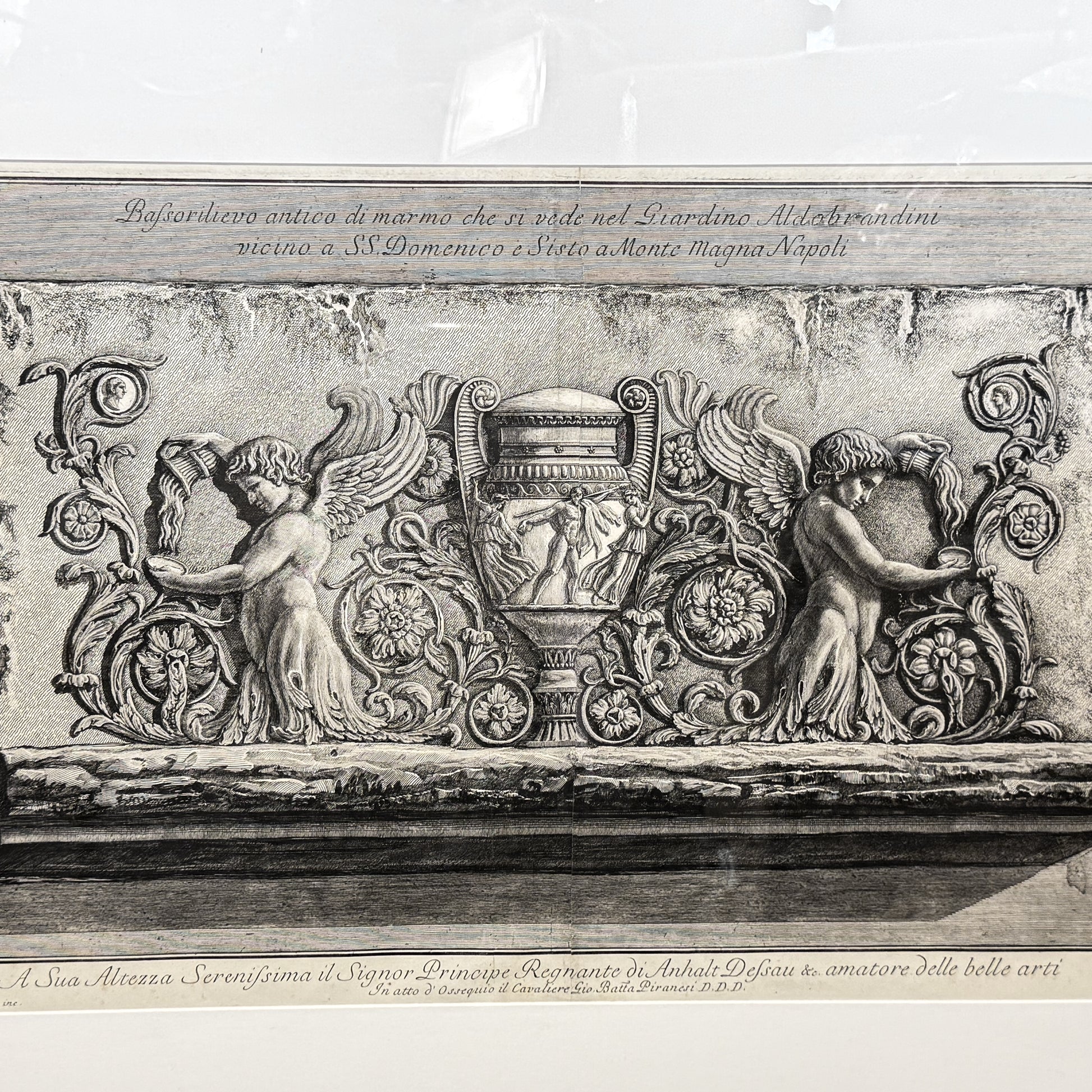 Decorative stone relief with cherubs and an urn on a marble surface