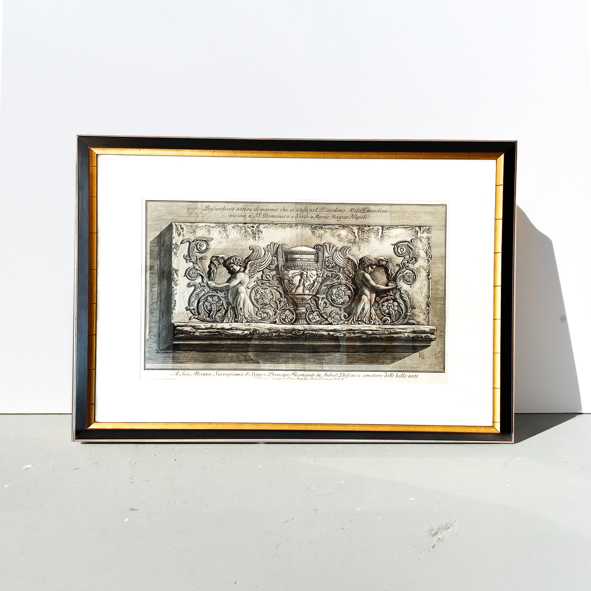 Framed artwork with classical design on a white surface