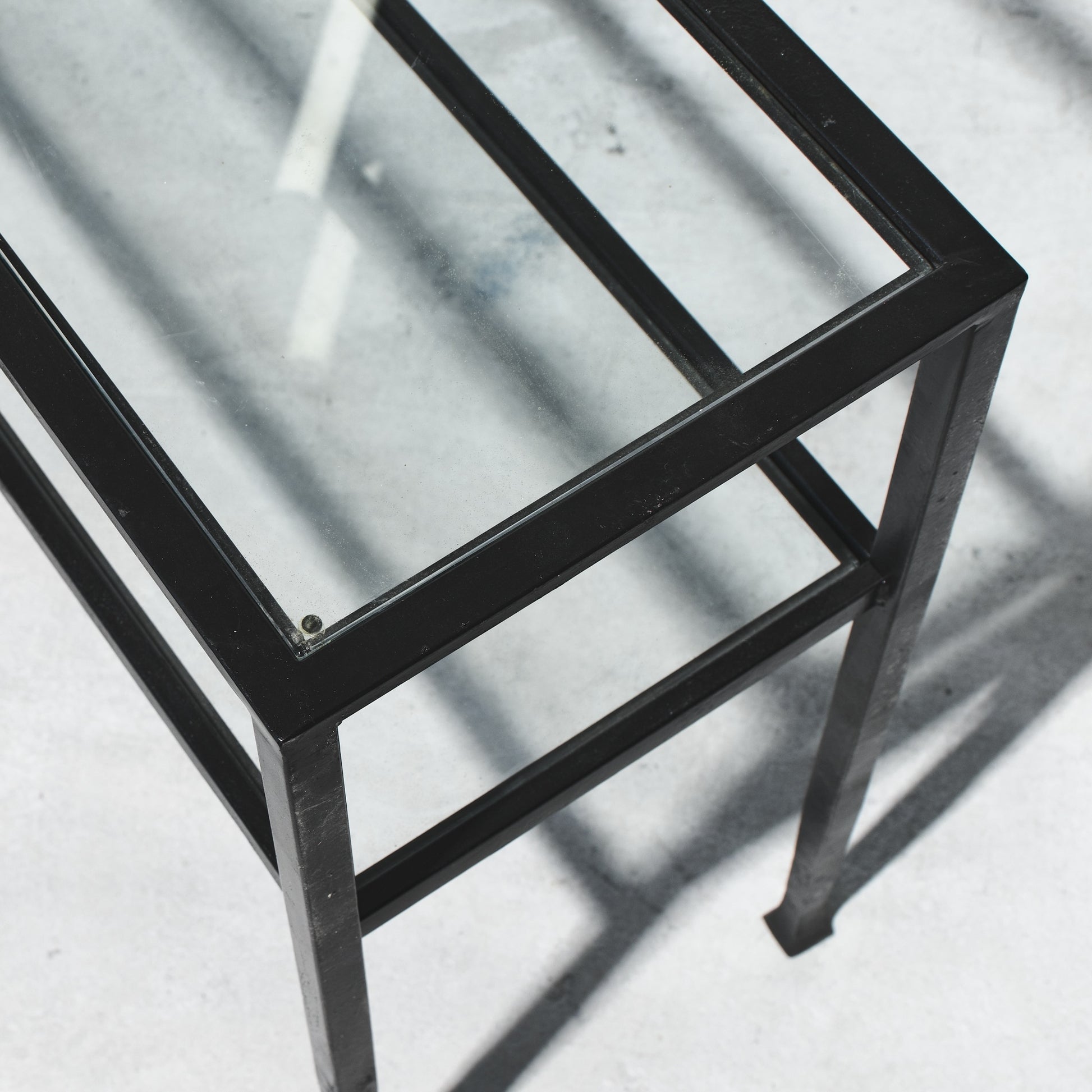 Glass table with black metal frame on a light gray background