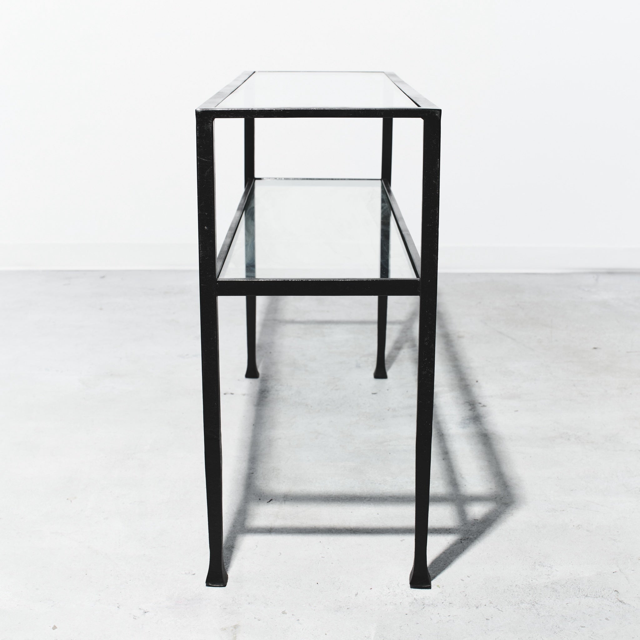 Glass display case with black metal frame on a white floor