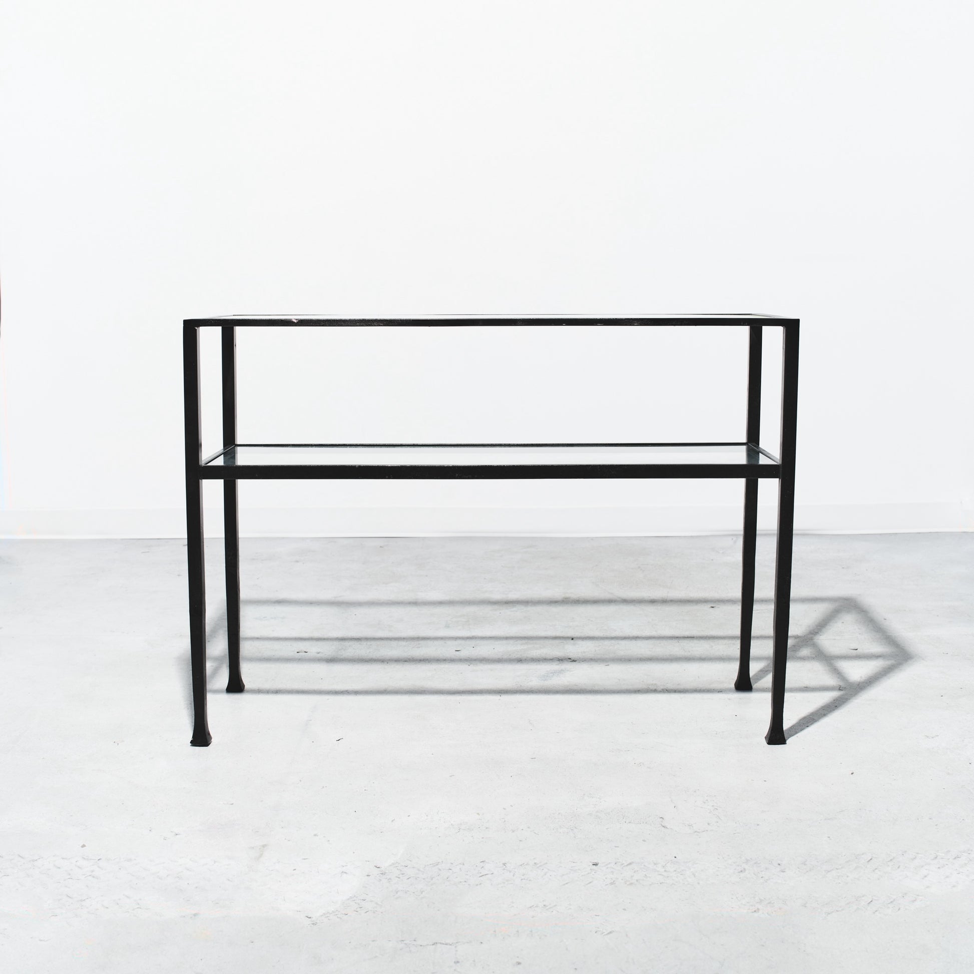 Black metal console table on a white floor with a white wall background