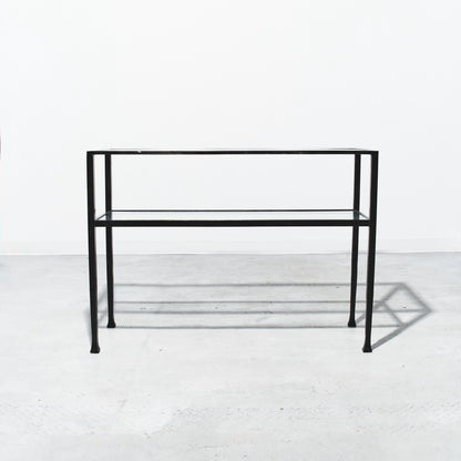 Black metal console table on a white floor with a white wall background